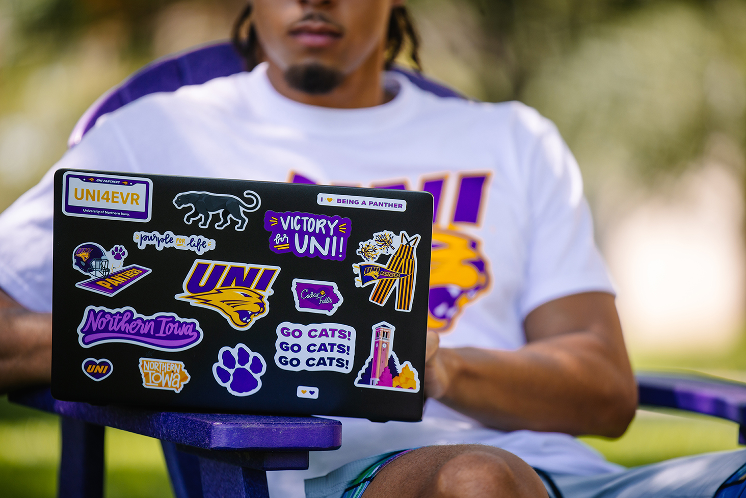 Student on laptop covered in purple and gold UNI stickers