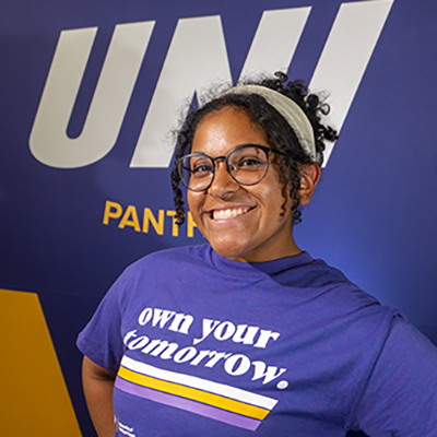 Addie smiling in a purple t-shirt that reads "own your tomorrow."
