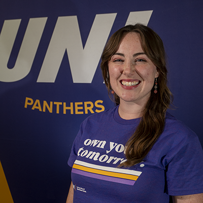 Aleigha smiling in a purple t-shirt that reads "own your tomorrow."