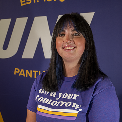 Allison smiling in a purple t-shirt that reads "own your tomorrow."