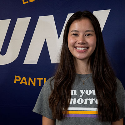 Amory smiling in a gray t-shirt that reads "own your tomorrow."