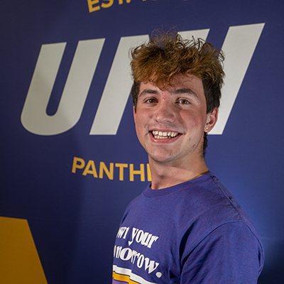 Austin smiling in a purple t-shirt that reads "own your tomorrow."