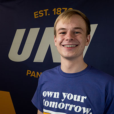 Bryce smiling in a purple t-shirt that reads "own your tomorrow."