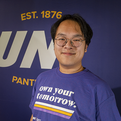Eric smiling in a purple t-shirt that reads "own your tomorrow."