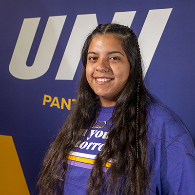 Estephany smiling in a purple t-shirt that reads "own your tomorrow."