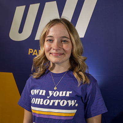 Esther smiling in a purple t-shirt that reads "own your tomorrow."