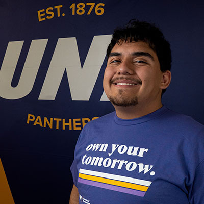 Gabriel smiling in a purple t-shirt that reads "own your tomorrow."