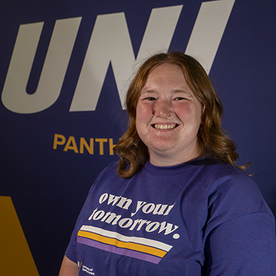 Grace smiling in a purple t-shirt that reads "own your tomorrow."