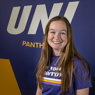 Grace smiling in a purple t-shirt that reads "own your tomorrow."