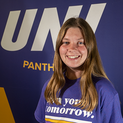 Grace smiling in a purple t-shirt that reads "own your tomorrow."