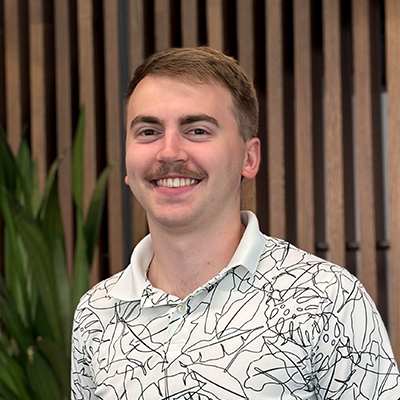 Grant smiling in front of a wood slat background