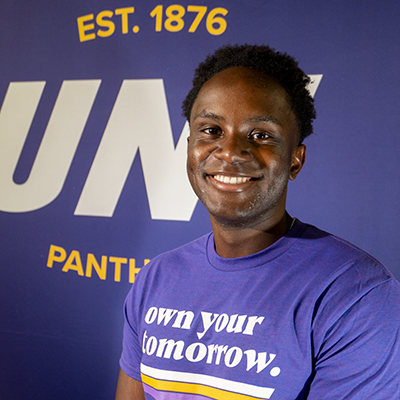 Ishimwe smiling in a purple t-shirt that reads "own your tomorrow."