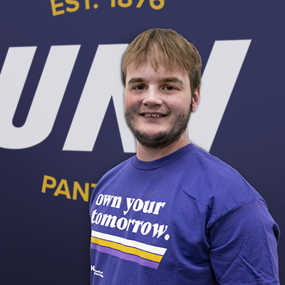 Jacob smiling in a purple t-shirt that reads "own your tomorrow."