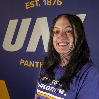 Kayla smiling in a purple t-shirt that reads "own your tomorrow."