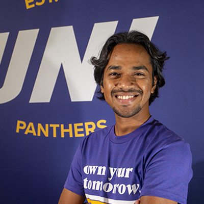 Khairul smiling in a purple t-shirt that reads "own your tomorrow."