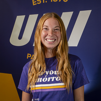 Lauren smiling in a purple t-shirt that reads "own your tomorrow."