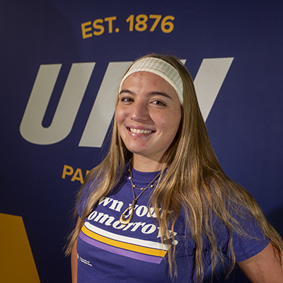 Laynee smiling in a purple t-shirt that reads "own your tomorrow."