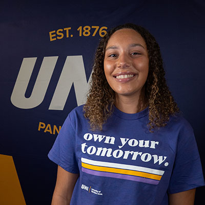 Makyla smiling in a purple t-shirt that reads "own your tomorrow."