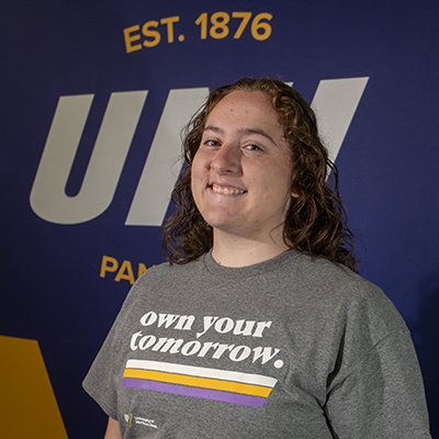 Meggan smiling in a gray t-shirt that reads "own your tomorrow."