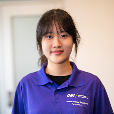 Minxi L. smiling in a purple UNI polo