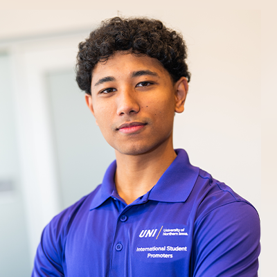 Nischal S. smiling in a purple UNI polo
