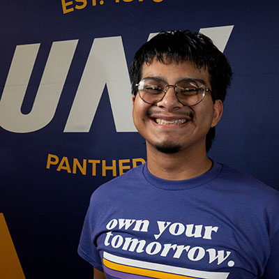 Osmar smiling in a purple t-shirt that reads "own your tomorrow."