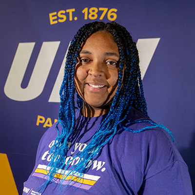 Quinci smiling in a purple t-shirt that reads "own your tomorrow."