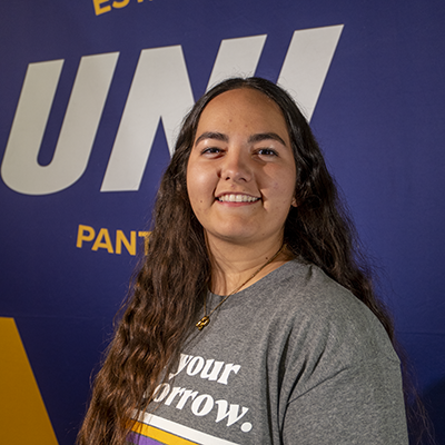 Roxanna smiling in a gray t-shirt that reads "own your tomorrow."