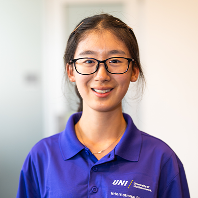 Shengyi H. smiling in a purple UNI polo