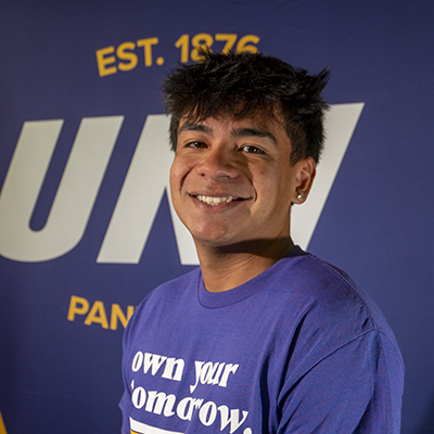 Steadman smiling in a purple t-shirt that reads "own your tomorrow."