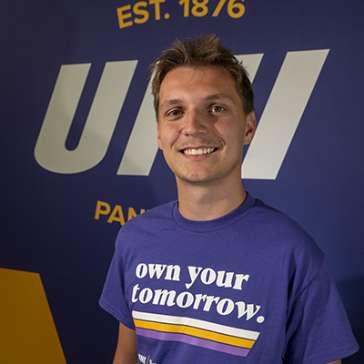 Tarik smiling in a purple t-shirt that reads "own your tomorrow."