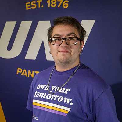 Terry smiling in a purple t-shirt that reads "own your tomorrow."