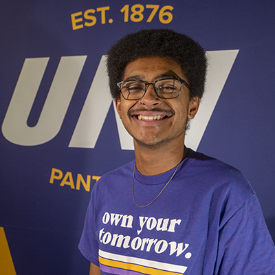 Tyson smiling in a purple t-shirt that reads "own your tomorrow."