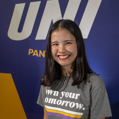 Vy smiling in a gray t-shirt that reads "own your tomorrow."