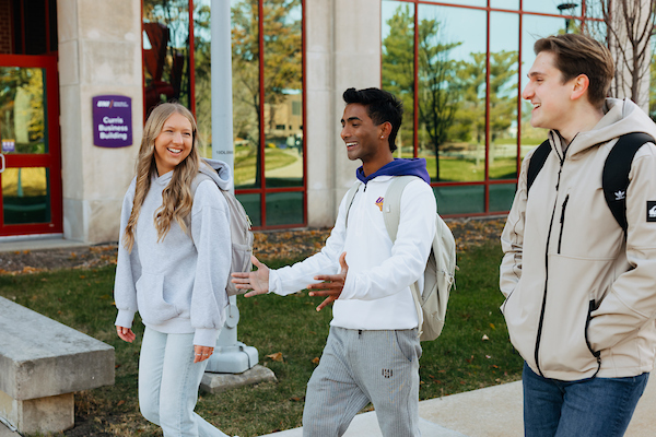 Three students walking on campus and laughing