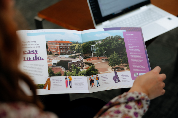 Up close of a student holding and looking at a view book.