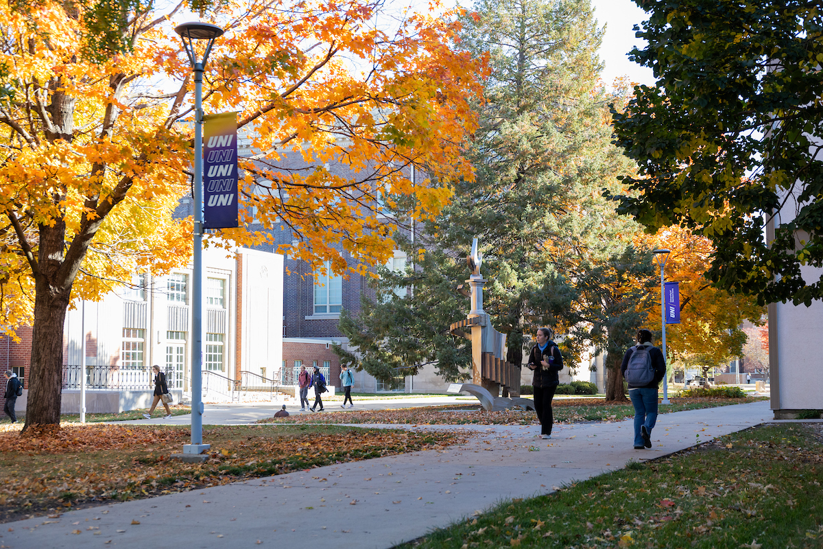 Picture of UNI campus in the fall with students walking around outside.