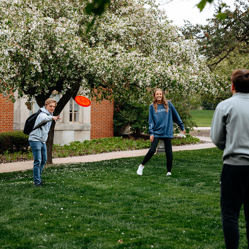 Students throwing a frisbee on campus