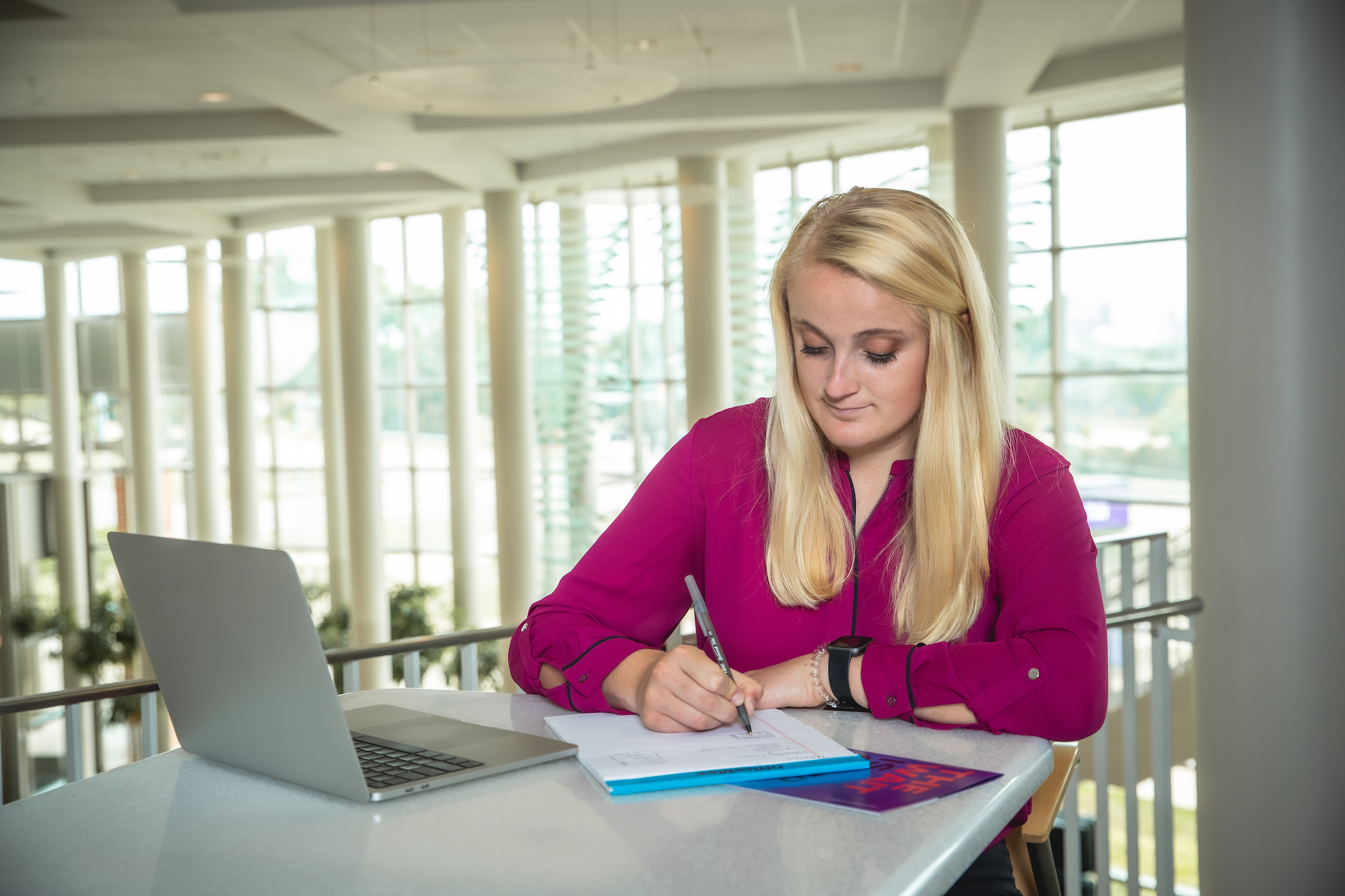 Student sitting at table, writing on a notebook