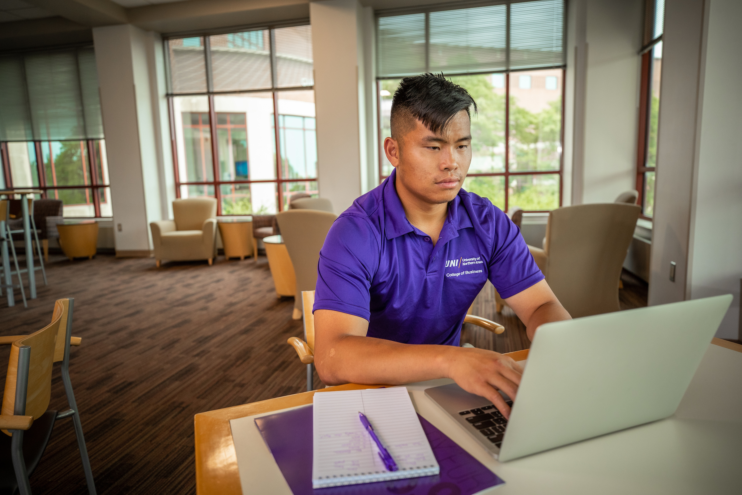 Student sitting on desk, typing on laptop